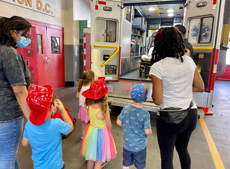 Children at a firehouse getting a tour of an ambulance