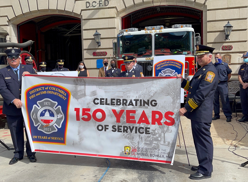 Firefighters holding a banner celebrating 150 years of service